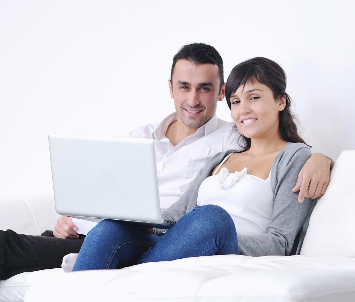 Mies ja nainen istuvat sohvalla hymyillen